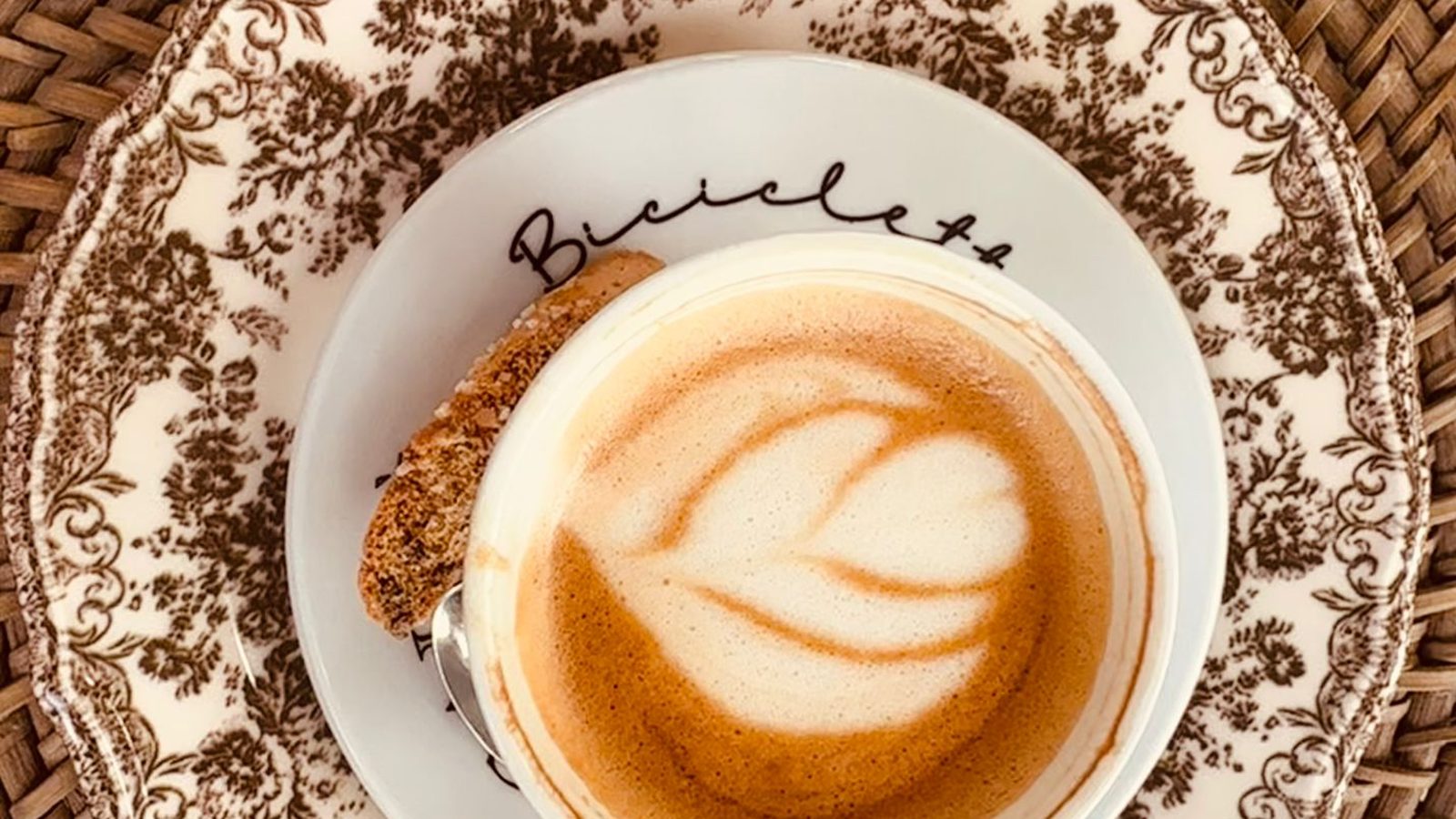 Cappuccino met latte art op een klassiek bord bij Bici Caffè